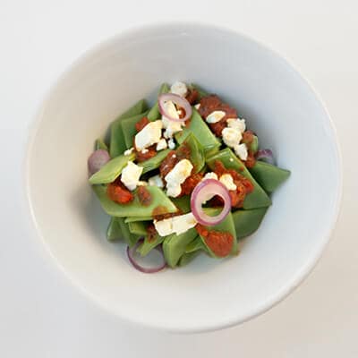 Mange-tout à la tomate, à la feta et aux oignons rouges